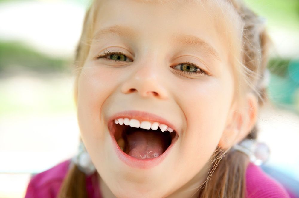 Young girl opening mouth and showing baby teeth